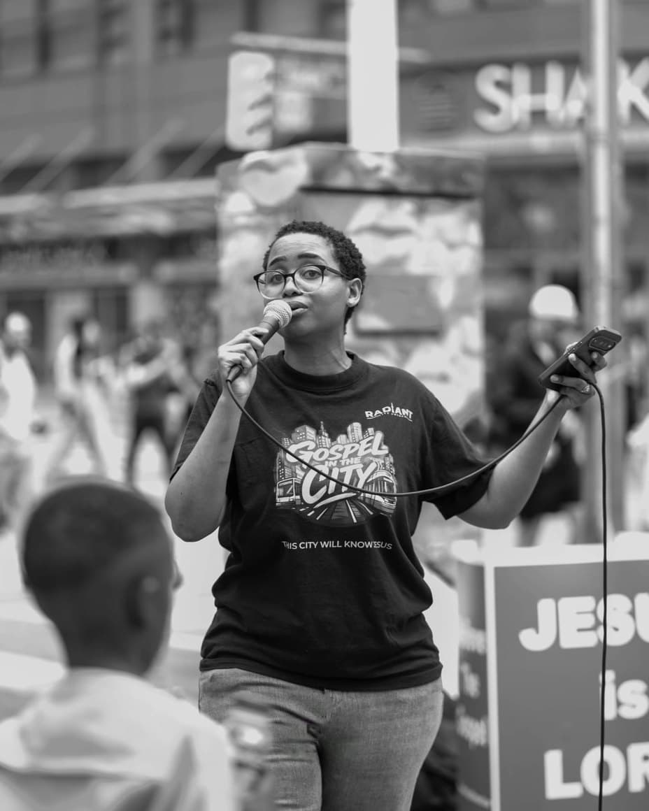 Lerato preaching into a microphone on a downtown street